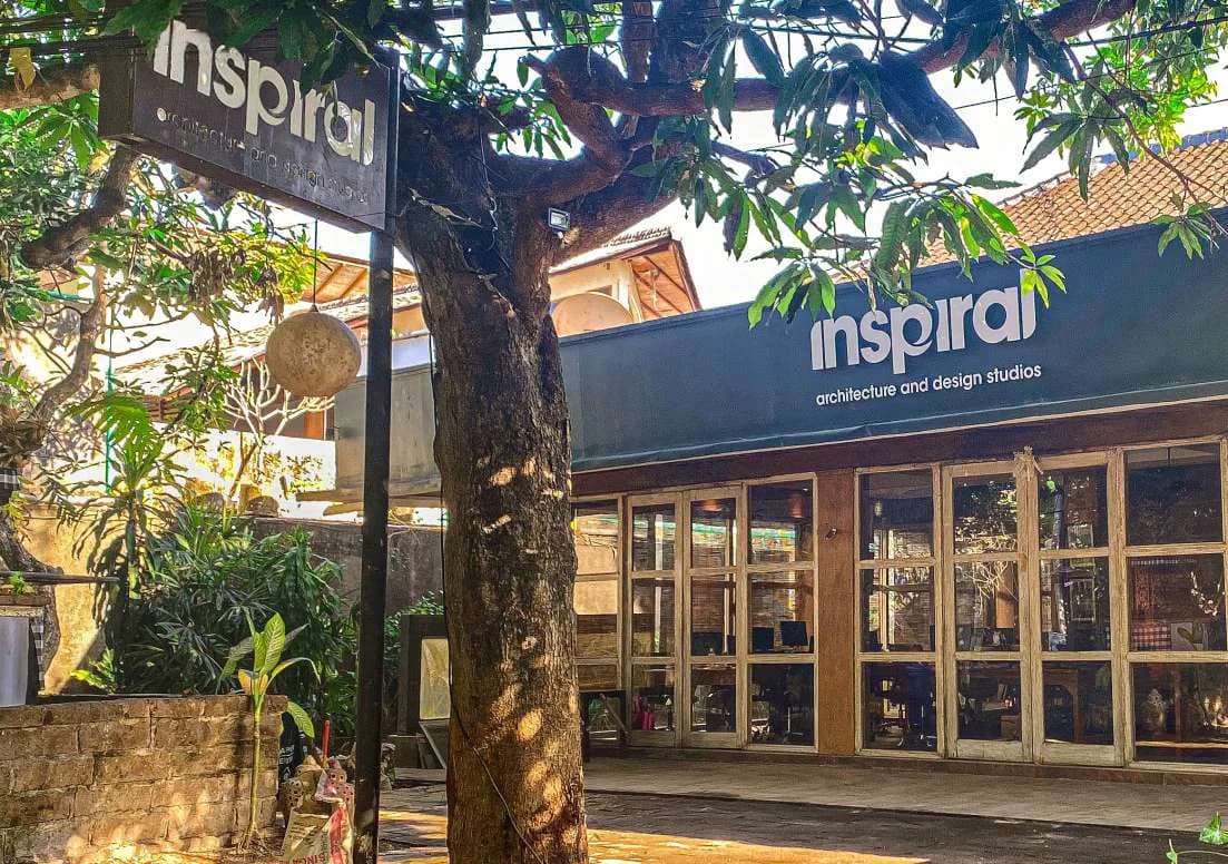 The Inspiral studio in Bali, a low timber-fronted building under mature trees with the practice's signage