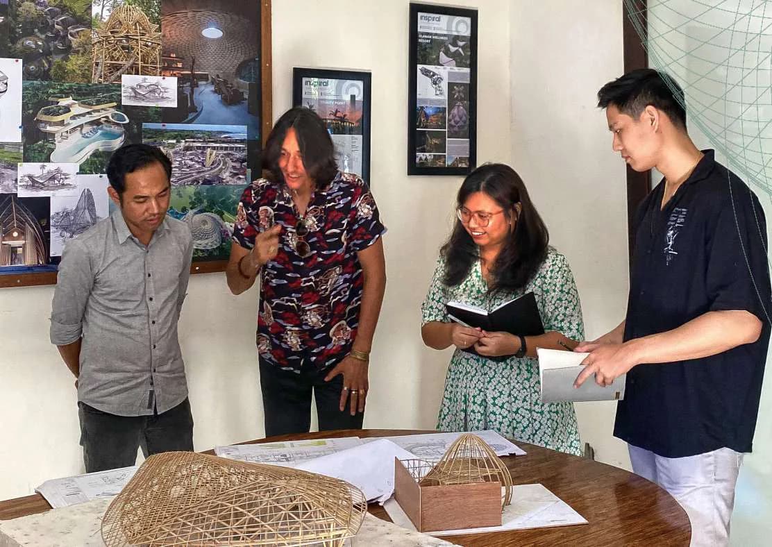 Four members of the Inspiral studio reviewing a physical architectural model on a table