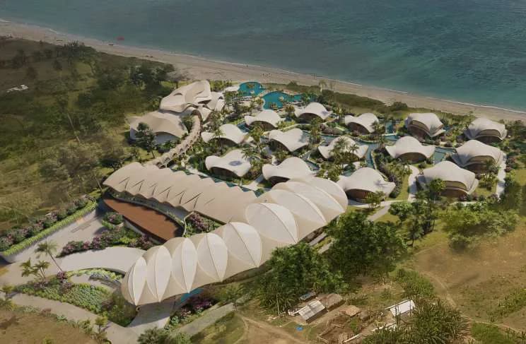 Aerial of a beachfront resort, low pavilions arranged along the shoreline
