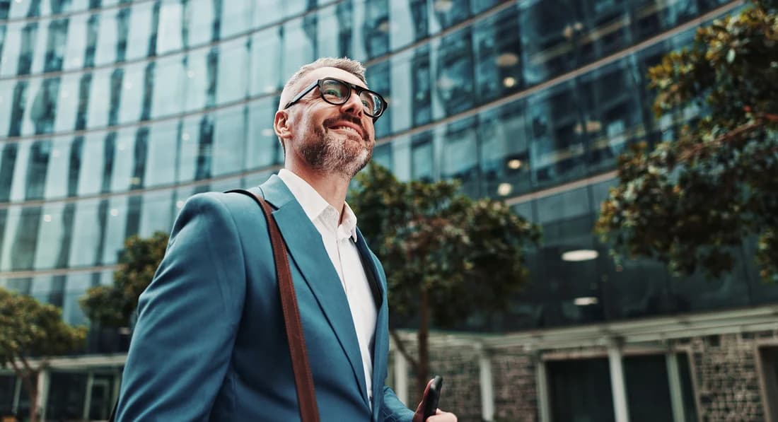 A man in a suit walking past a glass-fronted city office building