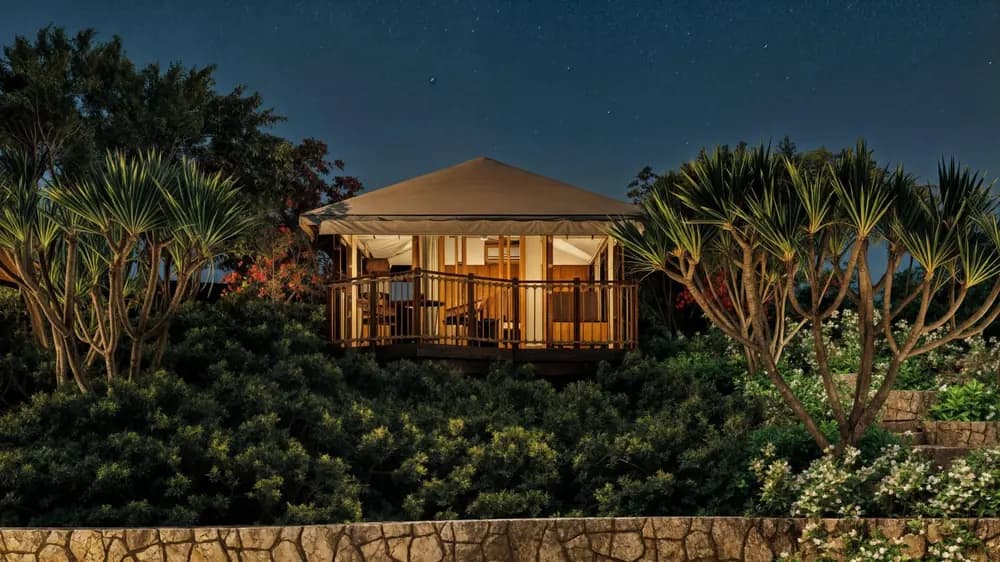 Tented pavilion villa at dusk in tropical planting